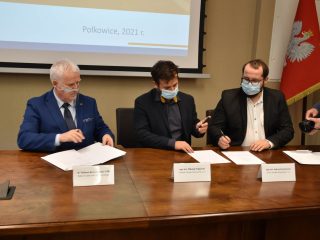 Uczestnicy podpisania porozumienia Scanway omawiają dokumenty przy stole.