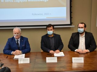 Trzej przedstawiciele pozują przy stole z dokumentami porozumienia UJW i Scanway.