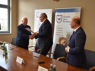 Sygnatariusze z dokumentami gratulują sobie podpisania porozumienia.
