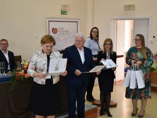 Organizatorzy trzymają otwarte teczki z dokumentami podczas wręczania nagród.