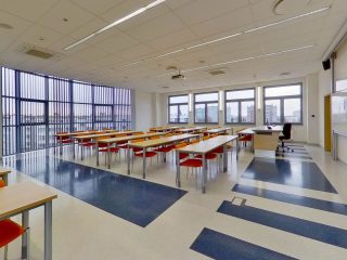 Panoramiczny widok sali ćwiczeniowej z dużymi oknami i tablicami.