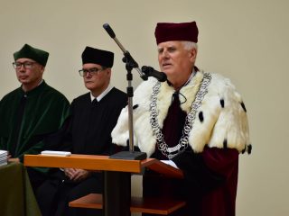 Mężczyzna w todze z gronostajowym płaszczem przemawia przy mównicy.