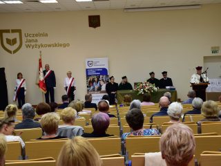 Widok auli podczas zakończenia roku PUTW, z pocztem sztandarowym i władzami uczelni.