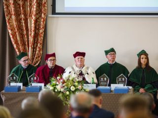 Władze uczelni w togach przy stole prezydialnym podczas inauguracji roku akademickiego 2022/2023.