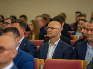 Mężczyźni w marynarkach słuchają wystąpienia podczas inauguracji roku akademickiego.