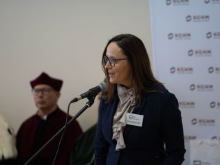 Kobieta w okularach i granatowej marynarce przemawia do mikrofonu podczas inauguracji.