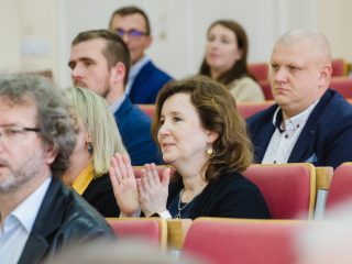 Kobieta klaszcze wśród publiczności wręczenia nagród.