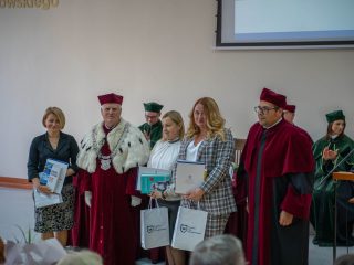 Trzy kobiety z dyplomami, książkami i torbami pozują obok rektora i przedstawiciela uczelni.