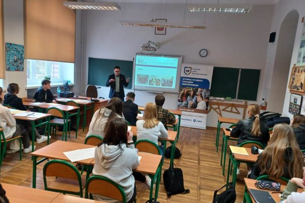 Uczniowie słuchają prezentacji UJW w sali lekcyjnej.
