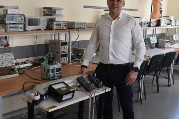 Absolwent mechatroniki przy stanowisku laboratoryjnym z aparaturą pomiarową.