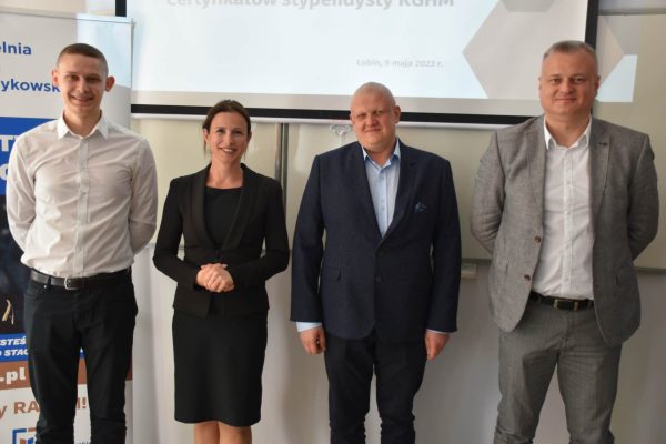 3 mężczyzn i 1 kobieta pozują przy ścianie