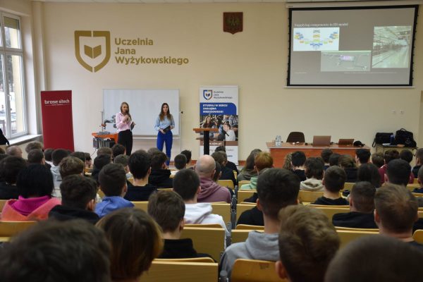 Prezentacja przy stanowisku z robotem przed publicznością w auli UJW.
