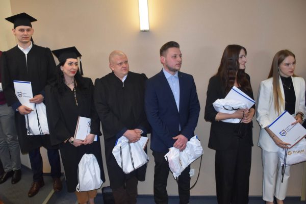 Absolwenci z dyplomami i upominkami pozują podczas uroczystości w UJW.