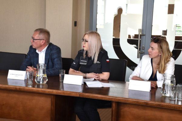 Uczestnicy spotkania partnerskiego, w tym funkcjonariuszka, siedzą przy stole konferencyjnym.