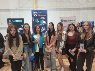 Grupa uczestniczek targów edukacyjnych z ulotkami przy stoisku UJW.