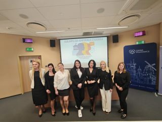 Uczestniczki Ogólnopolskiej Konferencji Studenckiej pozują przed ekranem w sali konferencyjnej.