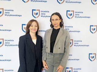 Dwie uczestniczki konferencji pozują na tle ścianki z logo UJW.