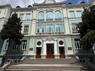 Reprezentacyjna fasada uczelni z szerokimi schodami prowadzącymi do wejścia.