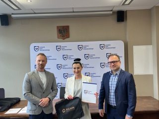 Wyróżniona z certyfikatem KGHM i torbą upominkową pozuje pomiędzy dwoma wręczającymi.
