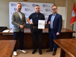 Wyróżniony w granatowej koszulce polo pozuje z certyfikatem i upominkiem.
