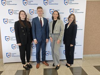 Czworo uczestników konferencji studenckiej na tle ścianki z logo UJW.