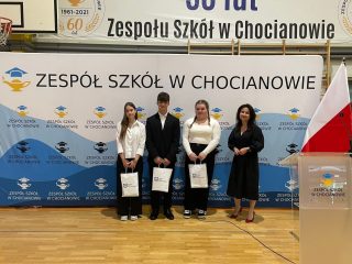 Czworo uczestników pozuje z torbami UJW na tle ścianki Zespołu Szkół w Chocianowie.