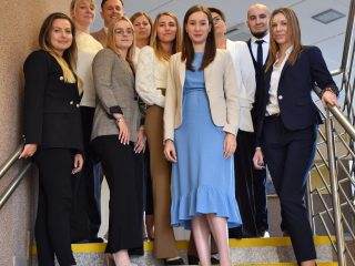 Uczestnicy obron zarządzania pozują przy poręczy schodów w budynku uczelni.