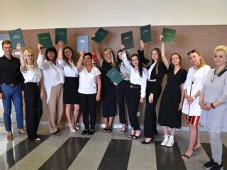 Absolwentki pedagogiki unoszą zielone prace dyplomowe na wspólnym zdjęciu.
