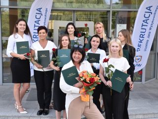 Absolwentki pedagogiki z pracami i kwiatami pozują przed wejściem do UJW.