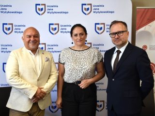 Troje uczestników podpisania umowy pozuje na tle ścianki UJW.