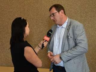Mężczyzna w jasnej marynarce udziela wywiadu dziennikarce z mikrofonem.