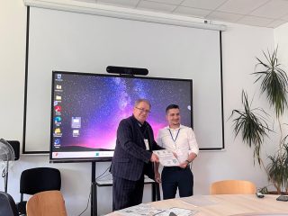 Dwaj mężczyźni podają sobie dłonie podczas spotkania w sali konferencyjnej.