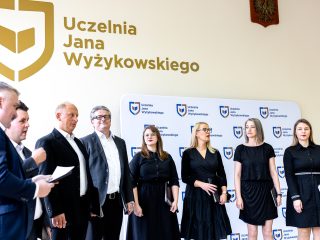 Chór z partyturami występuje pod napisem Uczelnia Jana Wyżykowskiego.
