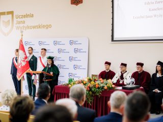 Przemówienie podczas inauguracji roku akademickiego, obok pocztu sztandarowego i władz w togach.
