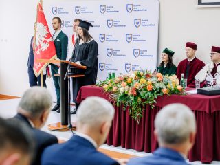 Osoba w zielonym stroju akademickim przemawia przy mównicy podczas inauguracji.