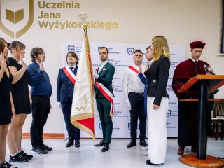 Uczestnicy uroczystości składają ślubowanie z uniesionymi prawymi dłońmi przy sztandarze.