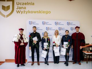 Wyróżnieni z dokumentami, różami i torbami UJW na wspólnym zdjęciu z władzami uczelni.