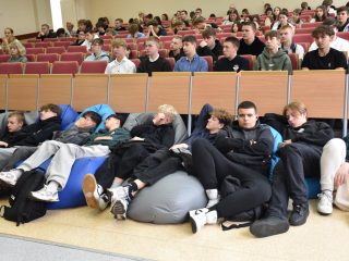 Uczestnicy festiwalu słuchają wykładu, siedząc w fotelach oraz na pufach przed widownią.