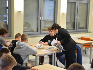 Prowadząca omawia z uczniami materiały rozłożone na stoliku.
