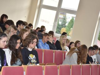 Uczestnicy Dolnośląskiego Festiwalu Nauki siedzą w auli przy oknach.