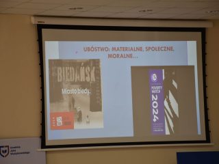 Slajd „Ubóstwo: materialne, społeczne, moralne...” z okładkami książek „Miasto biedy” i „Powrót do Reims”.