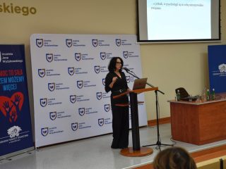 Prelegentka przy mównicy prowadzi wystąpienie podczas konferencji „Pomoc daje moc!”.