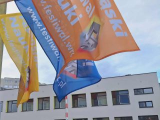 Flagi Dolnośląskiego Festiwalu Nauki przed budynkiem UJW.