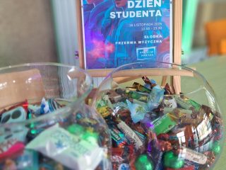 Cukierki w szklanych naczyniach obok plakatu Dnia Studenta UJW.