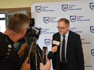 Operator filmuje wywiad z mężczyzną w okularach przed ścianką UJW.