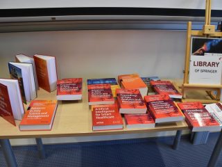 Książki naukowe na stole ekspozycyjnym z tabliczką „Library of Springer”.