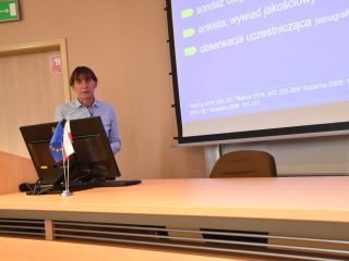 Prelegent przy mównicy prezentuje slajd dotyczący metod badawczych podczas konferencji o społecznościach lokalnych.