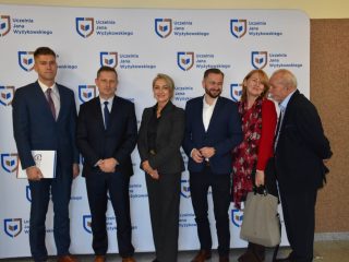 Sześcioro uczestników konferencji pozuje do zdjęcia na tle logo UJW.