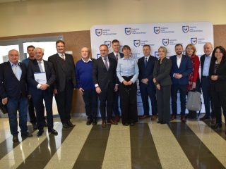 Uczestnicy konferencji o społecznościach lokalnych pozują wspólnie przy ściance UJW.