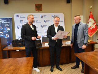 Odczytywanie certyfikatu dla uczestnika w jasnoniebieskiej marynarce.